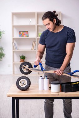 Kaykay tamir eden genç bir erkek tamirci.