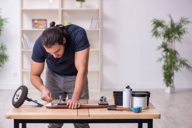 Kaykay tamir eden genç bir erkek tamirci.