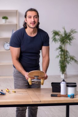 Kaykay tamir eden genç bir erkek tamirci.