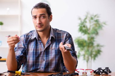 Cep telefonunu tamir eden genç bir teknisyen.