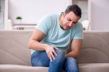 Evde acı çeken yaralı genç adam.