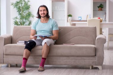 Genç bacak yaralı öğrenci evde çalışıyor.