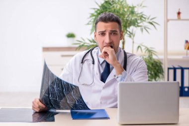 Klinikte çalışan genç erkek doktor.