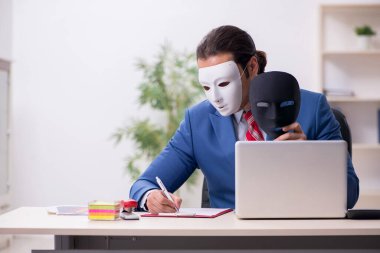 İkiyüzlülük konseptinde maske takan erkek çalışan.