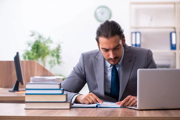 Ung manlig affärsman läser böcker på arbetsplatsen — Stockfoto