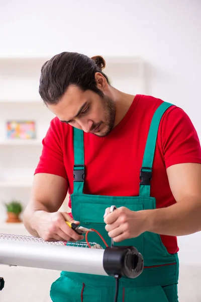 Jovem empreiteiro masculino reparando aquecedor dentro de casa — Fotografia de Stock