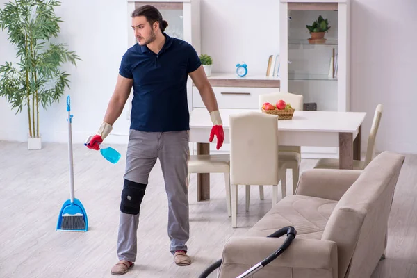 Young leg injured contractor cleaning the house — Stock Photo, Image