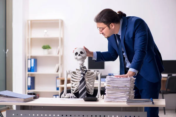 Joven empleado masculino con esqueletos en la oficina —  Fotos de Stock