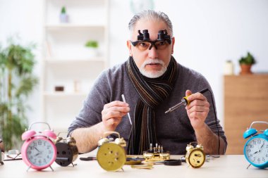 Atölyede çalışan yaşlı bir erkek saatçi.