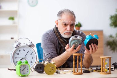 Atölyede çalışan yaşlı bir erkek saatçi.