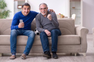 Baba oğul televizyonda maç izliyorlar.