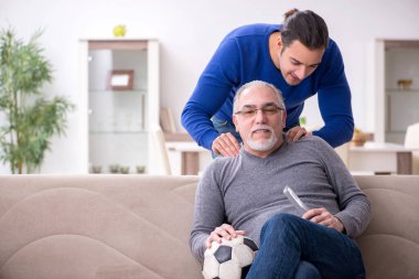 Baba oğul televizyonda maç izliyorlar.