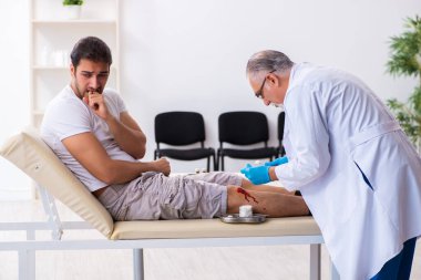Yaralı adam ilk yardım konseptinde yaşlı doktoru ziyaret ediyor.