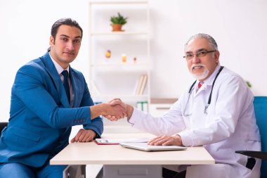 Genç işadamı yaşlı doktorla görüşüyor.