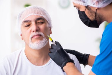 Yaşlı adam estetik ameliyat için erkek doktoru ziyaret ediyor.