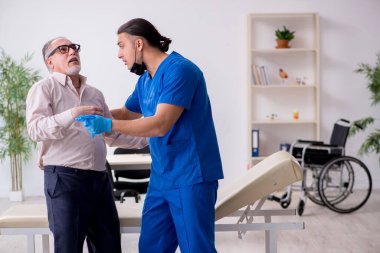 Yaşlı hasta genç erkek doktoru ziyaret ediyor.