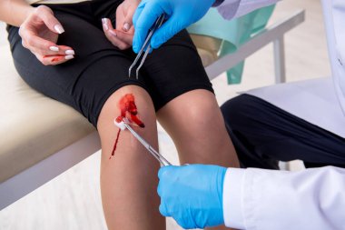 Erkek doktoru ziyaret eden bacağı yaralı bir kadın.