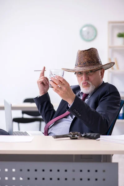 Смешной старый босс в ковбойской шляпе в офисе — стоковое фото