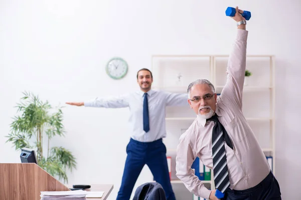 Dois funcionários fazendo exercícios físicos no local de trabalho — Fotografia de Stock