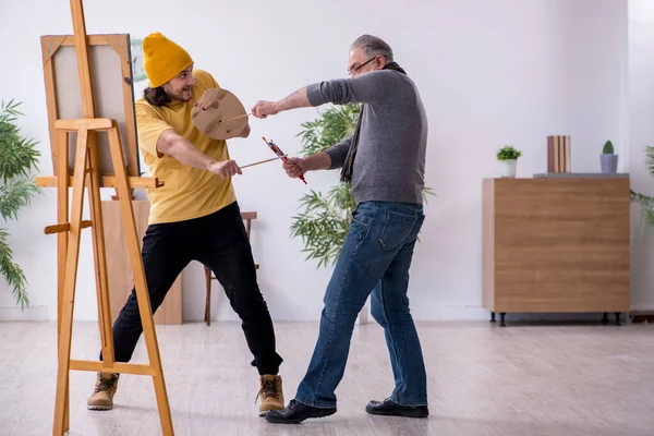 Old man taking lesson from young painter