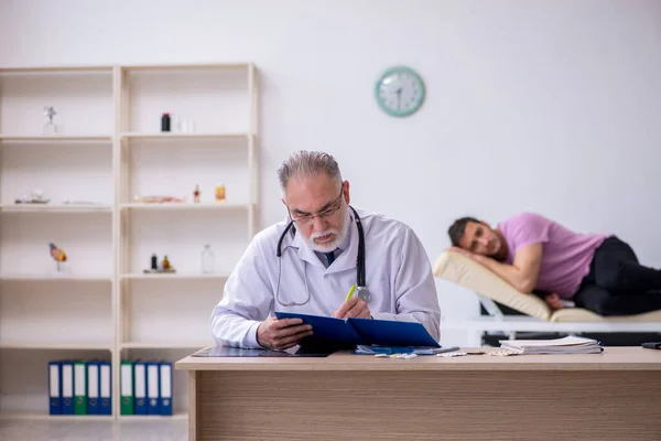 Giovane paziente maschio visita vecchio medico maschio — Foto Stock