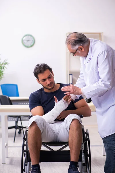 Genç yaralı adam deneyimli erkek doktor travmatologları ziyaret ediyor. — Stok fotoğraf