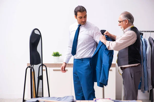 Jovem empresário visitando velho alfaiate masculino — Fotografia de Stock