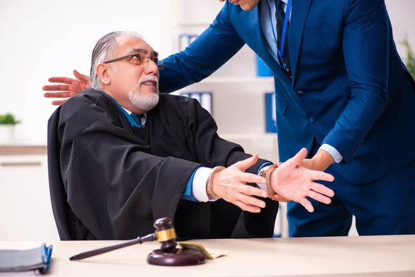 Inspector de policía arrestando a viejo juez en el tribunal — Foto de Stock