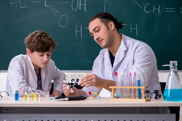 Młody nauczyciel chemii i uczeń w klasie — Zdjęcie stockowe