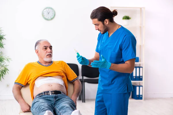 Old man visiting young male doctor — Stock Photo, Image