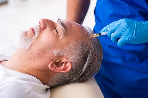 Old man visiting young male doctor in hair transplantation conce — Stock Photo, Image