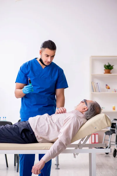 Vecchio paziente visita giovane medico maschile nel concetto di campionamento del sangue — Foto Stock