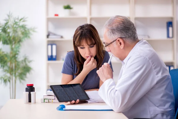 Genç bir kadın yaşlı bir doktoru ziyaret ediyor. — Stok fotoğraf