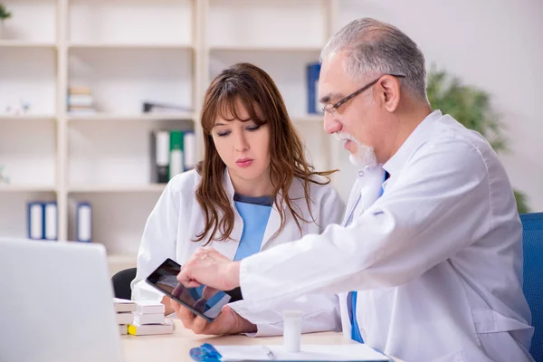 Yaşlı erkek doktor ve klinikteki genç bayan asistanı. — Stok fotoğraf