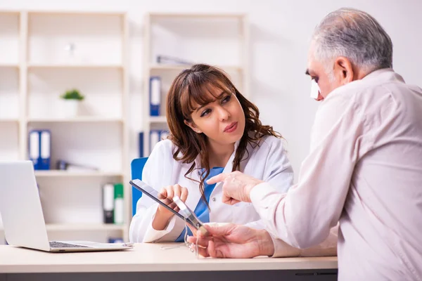 Anciano visitando a una joven doctora para cirugía plástica —  Fotos de Stock