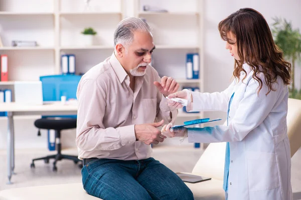 Yaşlı adam estetik ameliyat için genç bayan doktoru ziyaret ediyor. — Stok fotoğraf