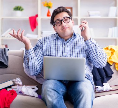 Dağınık odada çalışan genç adam.