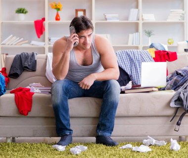 Dağınık odada çalışan genç adam.