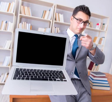 Kütüphanede çalışan boş ekran bilgisayarı olan bir iş adamı.