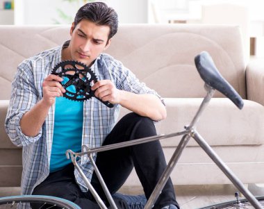 Evde bisiklet tamir eden genç bir adam.