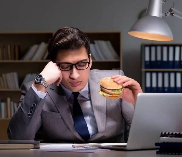 その実業家は夜遅くハンバーガーを食べて — ストック写真