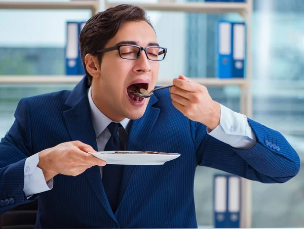 Funny businessman eating gold coins in office