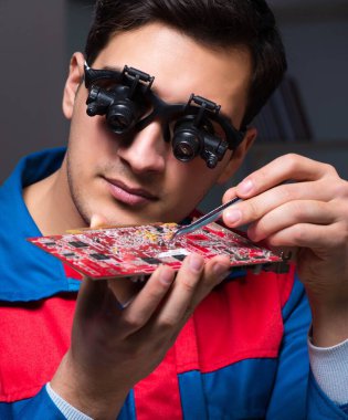 Bilgisayar uzmanı gece geç saatlerde bilgisayarı tamir ediyor.