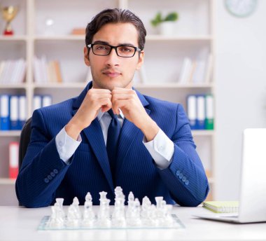 Genç işadamı ofiste cam satranç oynuyor.