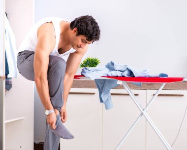 Genç adam yatak odasında ütü yapıyor.