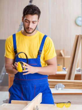 Genç tamirci marangoz daireler çizerek odun kesiyor.