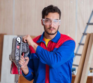 Elektrikli testereyle çalışan genç tamirci.