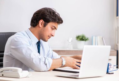 Genç yakışıklı işadamı ofiste çalışıyor.