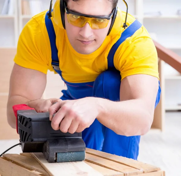 Carpintero reparador puliendo una tabla de madera con un po eléctrico —  Fotos de Stock