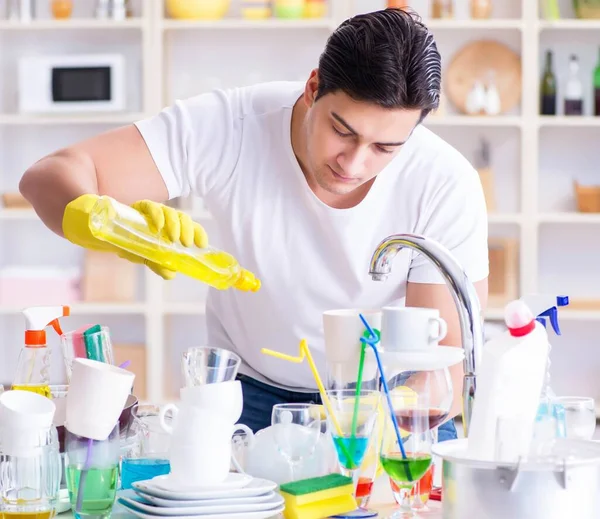 Мужчина наслаждается мытьем посуды дома — стоковое фото